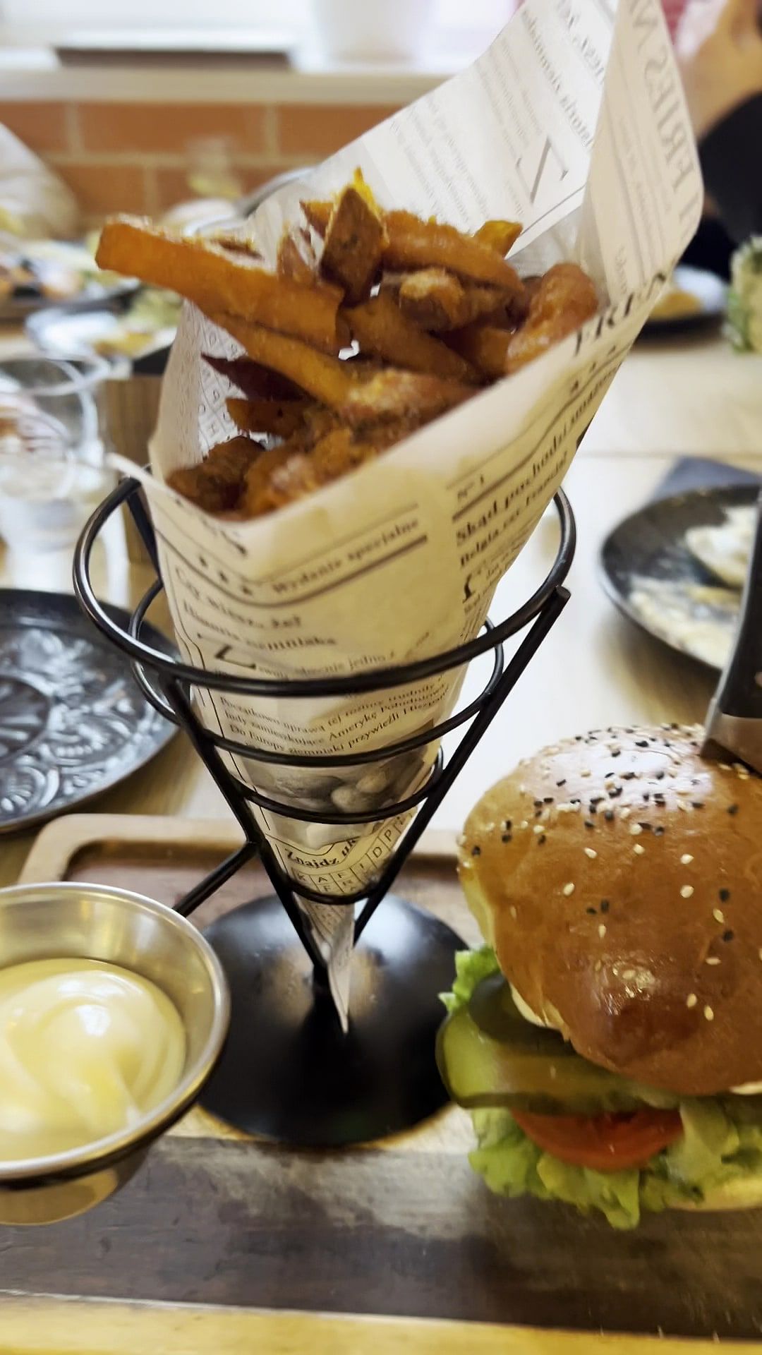 Burger kraftowy i frytki podane w papierowym rożku